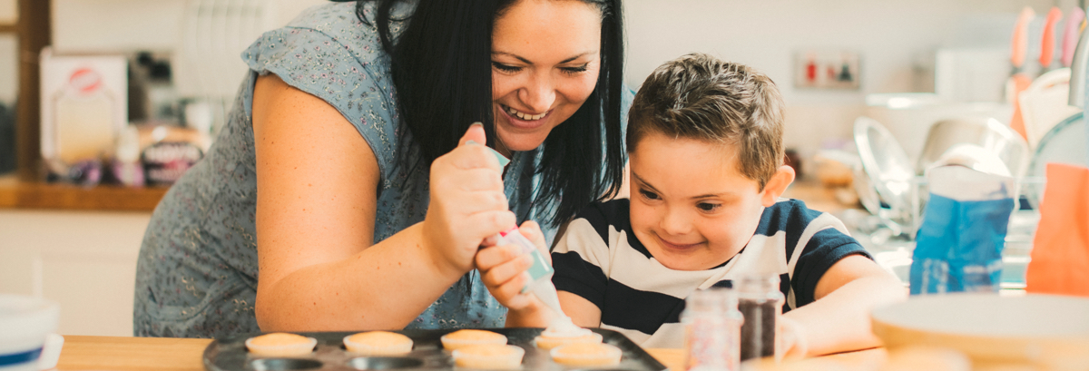 Une mère et son fils décorent des petits gâteaux dans la cuisine. 